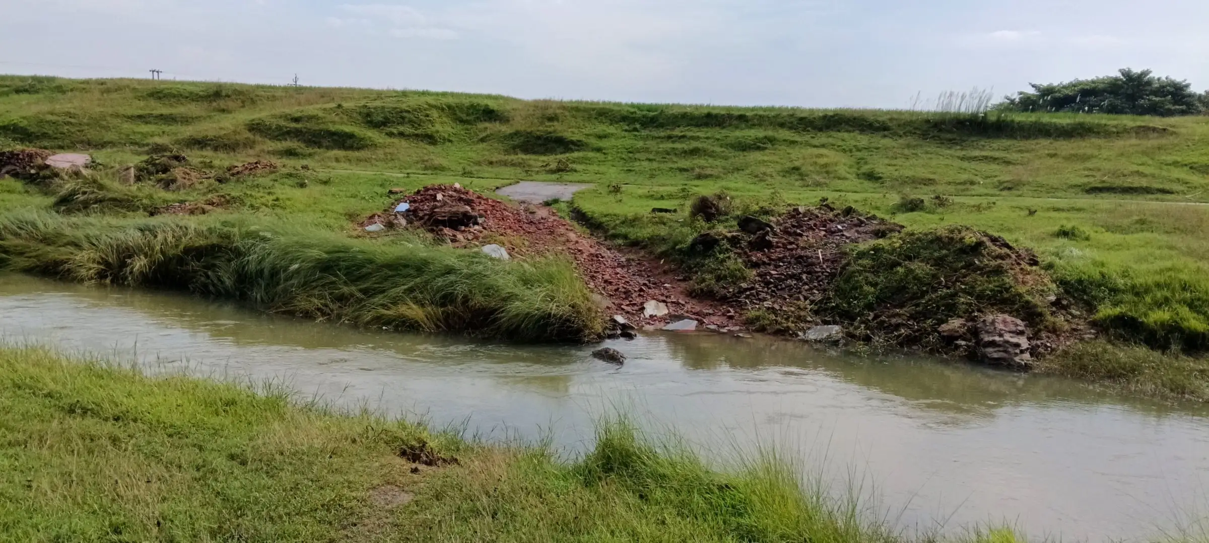 Eroded red-earth riverbank above a calm stream