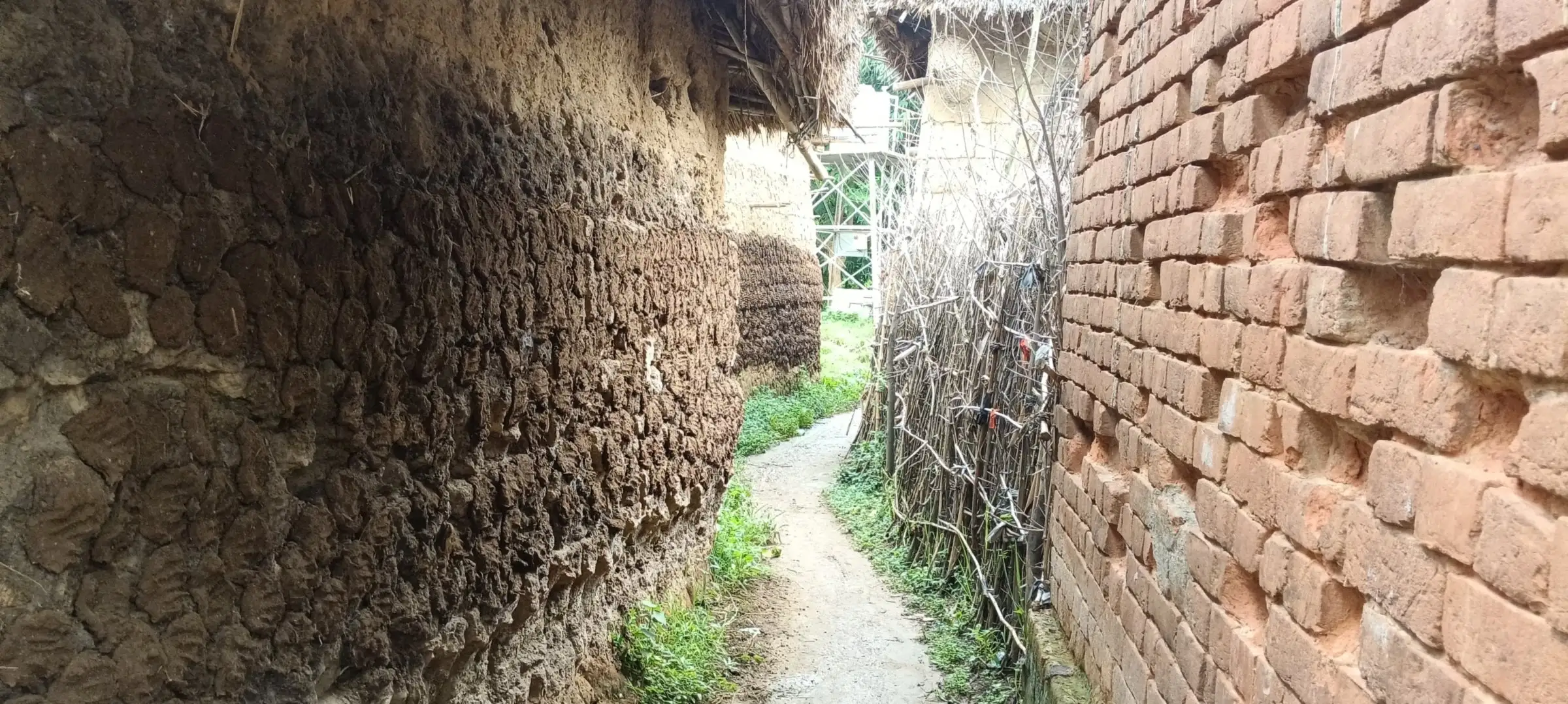 Tight alley between a mud wall and an exposed brick wall