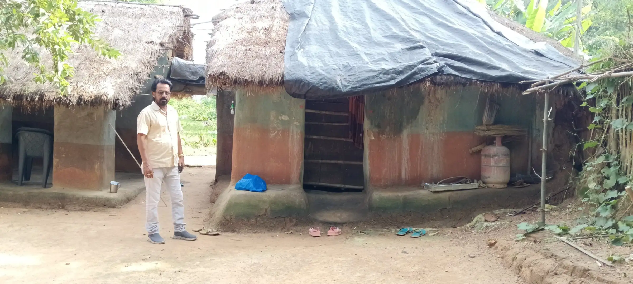 Mud hut with a tarpaulin roof in a village yard