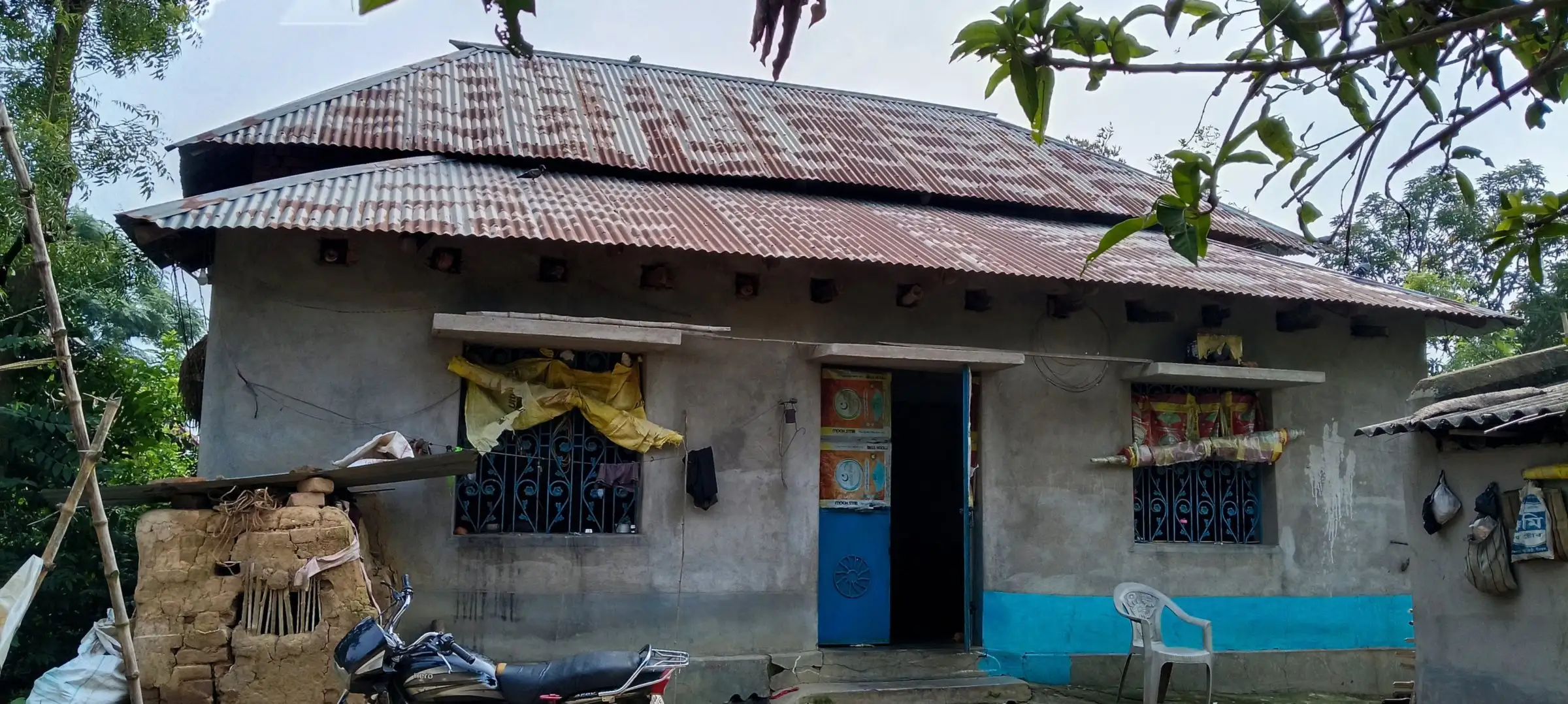 Concrete house with a tiered tin roof and blue trim