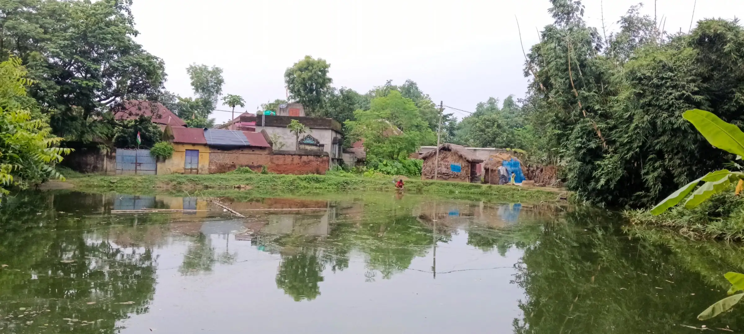 Still village pond reflecting houses and trees